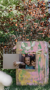 Kinder spielen mit Kartonhaus im Garten